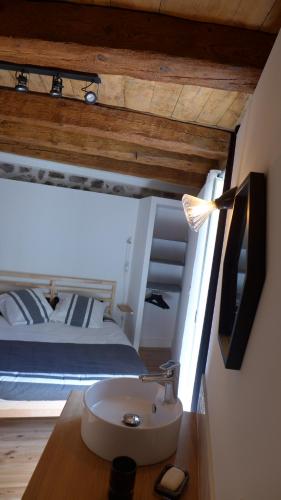 um quarto com uma cama, um lavatório e uma televisão em Gîte La Maison Toute de Travers em Le Malzieu-Ville
