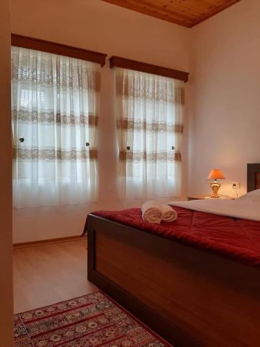 a bedroom with a large bed with red sheets and curtains at Grandpa’s Home in Gjirokastër