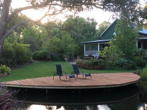 two chairs sitting on a wooden deck next to a house at Lakeside Garden Chalet in Denmark
