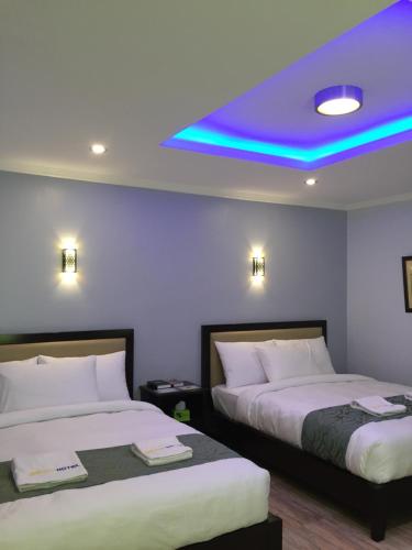 duas camas num quarto de hotel com tecto roxo em MAISON HOTEL em Cauayan City
