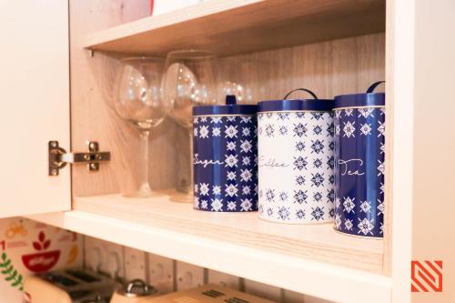 a shelf with blue and white cups and wine glasses at Modern Newgate Apartments - Convenient Location, Close to All Local Amenities in Stoke on Trent