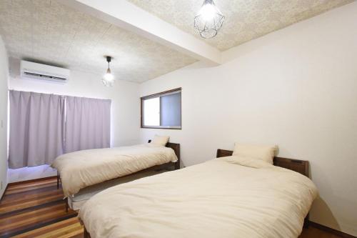 two beds in a room with white walls at 一棟貸し切り ゲストハウス Sai in Yasugi