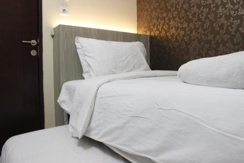 a bedroom with two beds with white sheets and pillows at Elegant 2BR Gateway Pasteur Apartment near Exit Toll Pasteur By Travelio in Bandung