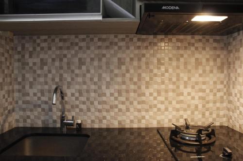 a tiled kitchen with a sink and a stove at Elegant 2BR Gateway Pasteur Apartment near Exit Toll Pasteur By Travelio in Bandung