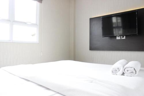 a bedroom with a bed with towels and a flat screen tv at Elegant 2BR Gateway Pasteur Apartment near Exit Toll Pasteur By Travelio in Bandung