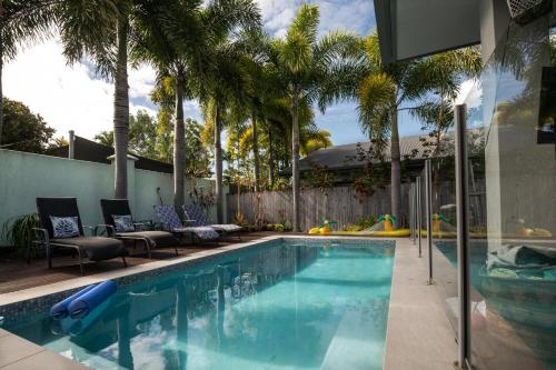 a swimming pool with palm trees in a backyard at Beach bliss, Netflix,Wifi in Kewarra Beach