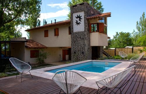 ein Haus mit einem Pool mit Stühlen und einer Uhr in der Unterkunft Las Espuelas Casas de Montaña in Potrerillos