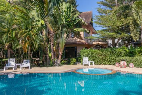 a swimming pool with two chairs and a house at Yuwadee Resort in Chalong 