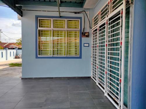 a blue wall with a window and a door at Nas Homestay in Jitra
