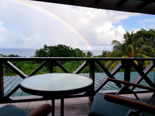 a balcony with a table and a rainbow at Rose Self Catering in Beau Vallon