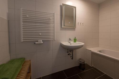 een witte badkamer met een wastafel en een bad bij Ferienwohnungen auf der Schleusenhalbinsel in Woltersdorf