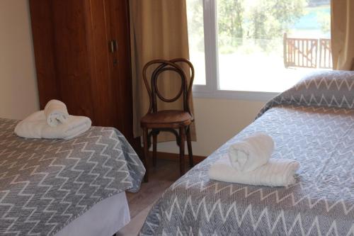a bedroom with a bed and a chair and a window at El Arrayan in Villa Pehuenia