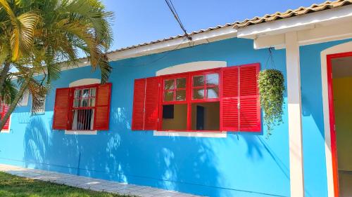 a blue house with red windows and a palm tree at Pequi hostel in Florianópolis