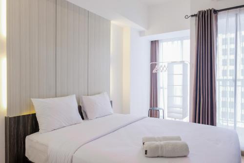 タンゲランにあるFully Parquette City View Studio Apartment at M-Town Residence By Travelioの大きなベッドとタオル2枚のある寝室