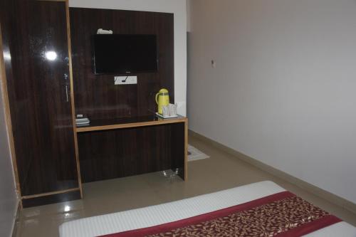 a room with a tv on a wooden stand with a mirror at The Leef Inn 500ms from Nakki Lake in Mount Ābu