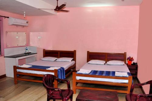 Arunaachalaa Inn في بالني: سريرين في غرفة مع كرسيين ومطبخ