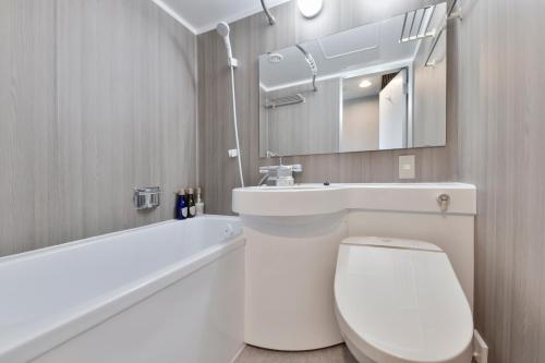a bathroom with a toilet and a sink and a mirror at Vessel Inn Keisei Tsudanuma Station in Narashino