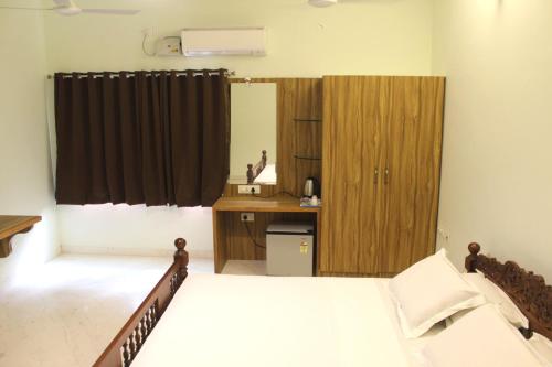 a bedroom with a bed and a wooden cabinet at Indian Residency in Tiruchchirāppalli