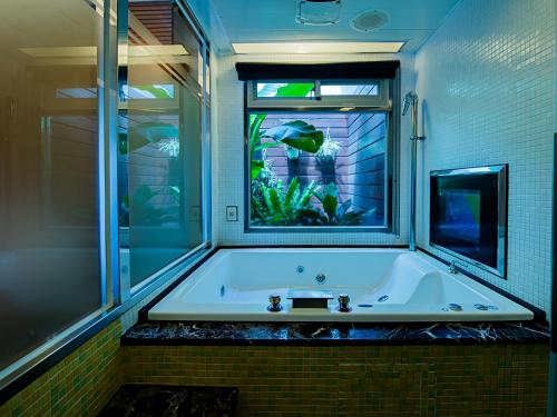 龍潭區的住宿－萊茵旅館，浴室设有浴缸,窗户上设有鱼缸