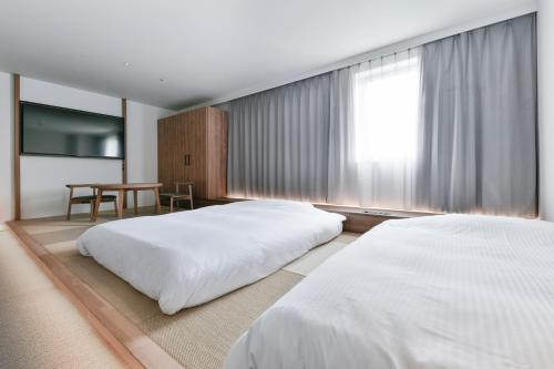 a hotel room with two beds and a table at Vessel Inn Keisei Tsudanuma Station in Narashino