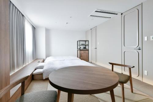 a bedroom with a bed and a table at Vessel Inn Keisei Tsudanuma Station in Narashino