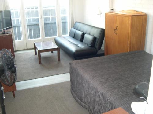 a room with a bed and a couch and a table at Strand Motel in Tauranga
