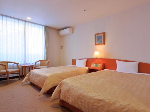 Habitación de hotel con 2 camas y mesa en ESCALE-YOKOHAMA en Yokohama