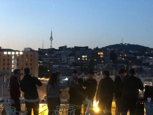a group of people standing on a rooftop at night at G Guesthouse Itaewon In Seoul in Seoul