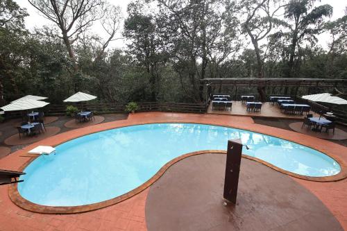 a large swimming pool with tables and chairs at Westend Hotel in Matheran