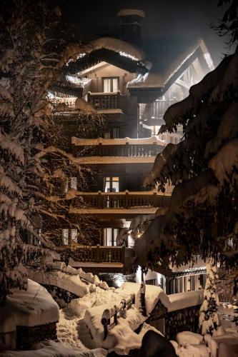 a building covered in snow with lights on it at Manali Lodge by Alpine Resorts in Courchevel