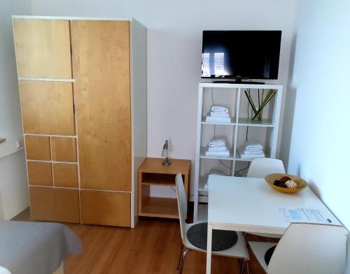 a living room with a white table and a tv at Horn Gästehaus in Leinfelden-Echterdingen