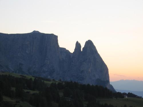 a mountain in the distance with the sun setting behind it at Villa Hubertus in Ortisei