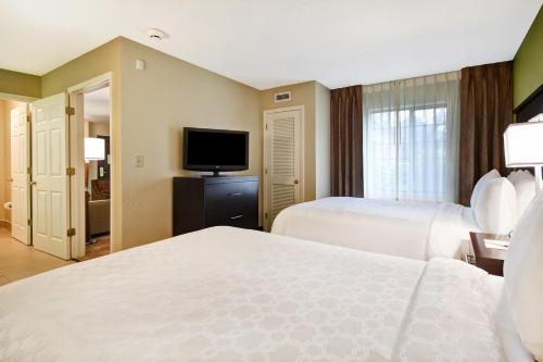a hotel room with two beds and a flat screen tv at Staybridge Suites Grand Rapids-Kentwood by IHG in Grand Rapids
