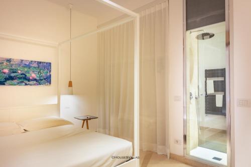 a white room with a bed and a glass shower at Archimede apartments in Siracusa