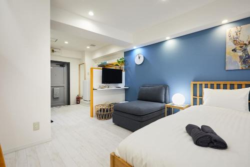 a bedroom with a blue wall and a bed and a chair at STAY ARI Kabukicho in Tokyo