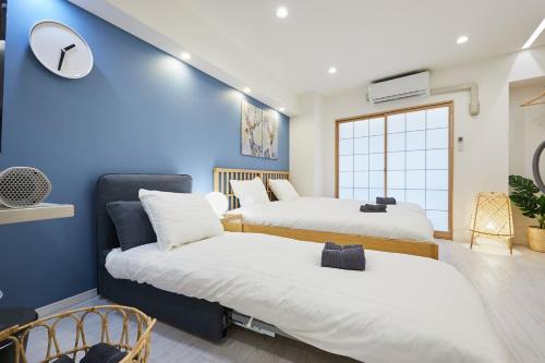 two beds in a room with blue walls at STAY ARI Kabukicho in Tokyo
