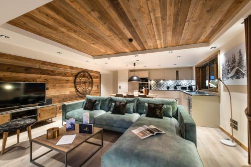 a living room with a couch and a tv at Manali Lodge by Alpine Resorts in Courchevel
