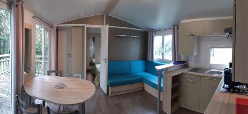 une petite cuisine avec une table et un mur bleu dans l'établissement Camping le Balcon de la Baie, à Saint-Marcan