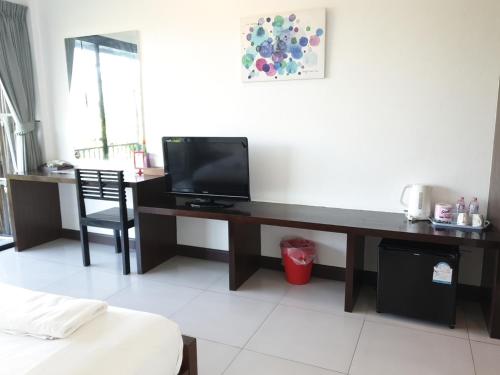 a room with a desk with a television on it at The Nidhra Boutique Resort in Baan Tai