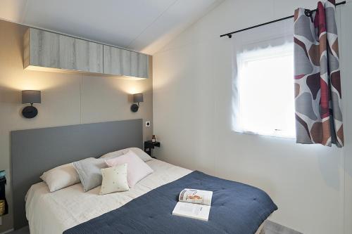 sypialnia z łóżkiem z niebieskim kocem i oknem w obiekcie Camping le Balcon de la Baie w mieście Saint-Marcan