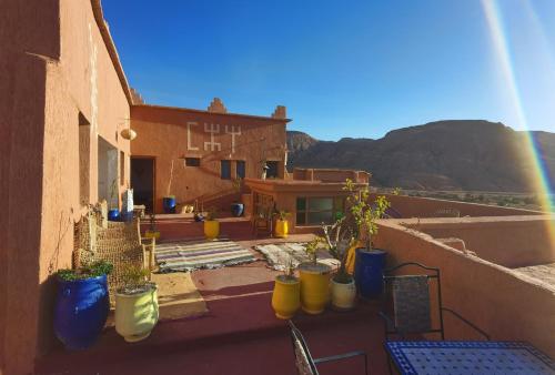 a group of potted plants on a balcony with a rainbow at Auberge Ayouze in Aït Ben Haddou