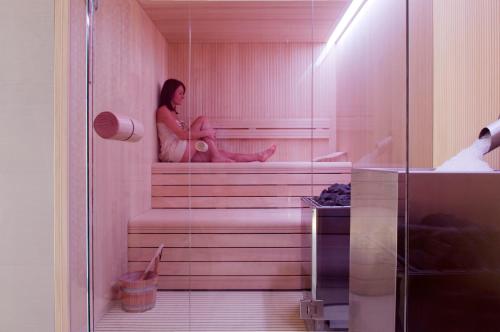 a woman is sitting in a sauna at Carbon Hotel in Genk