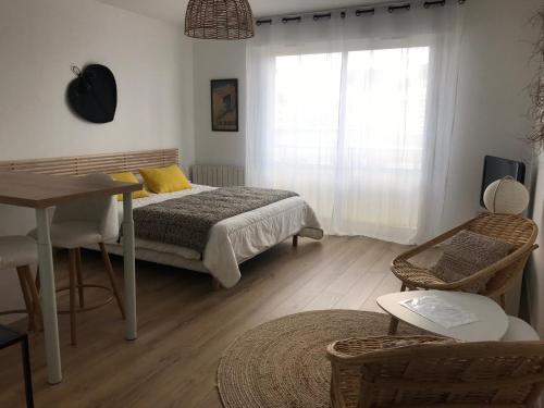 une chambre avec un lit, une table et une fenêtre dans l'établissement Studio neuf , à 2 pas de la plage et du port, au Pouliguen