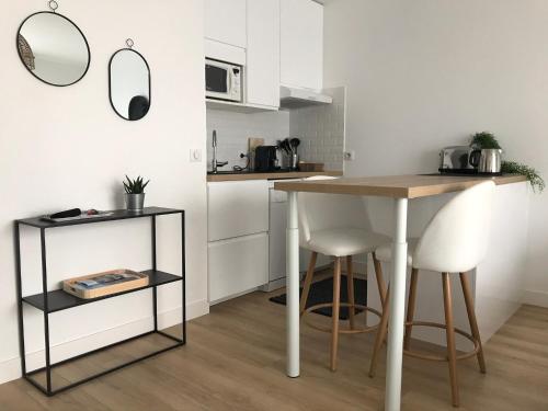 eine Küche mit einem Tisch und 2 weißen Stühlen in der Unterkunft Studio neuf , à 2 pas de la plage et du port in Le Pouliguen