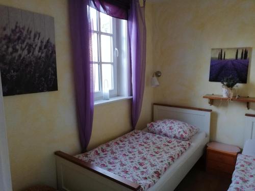 a bedroom with a bed and a window with purple curtains at Ferienhaus/Ferienwohnung Reinecke in Hodenhagen