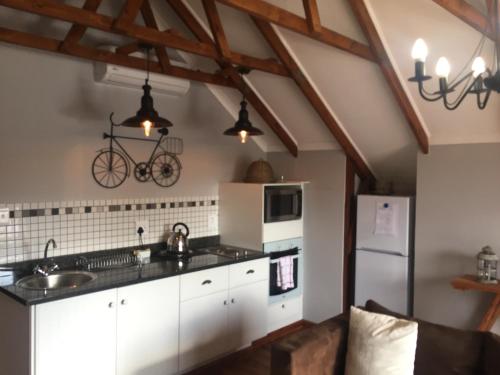 a kitchen with white cabinets and a bicycle on the wall at De Witte Loft in Newcastle