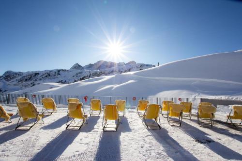 a group of yellow chairs sitting in the snow at Hotel Adler in Warth am Arlberg