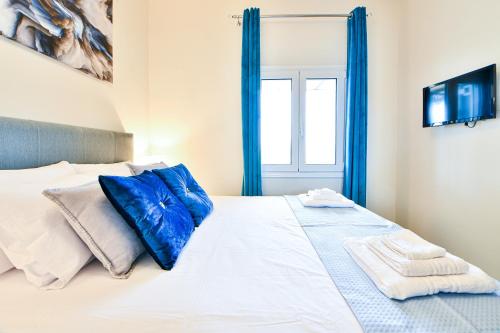 a bedroom with a large bed with blue curtains at Koukounari Luxury Apartments in Vathí
