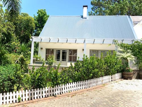 a white house behind a white picket fence at One Oak Guest House in Somerset West
