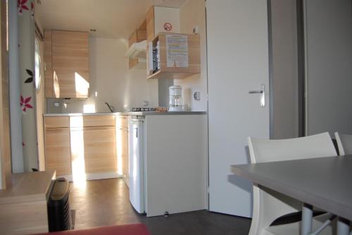 a kitchen with a white refrigerator and wooden cabinets at Camping Au Coeur de Vendome in Vendôme